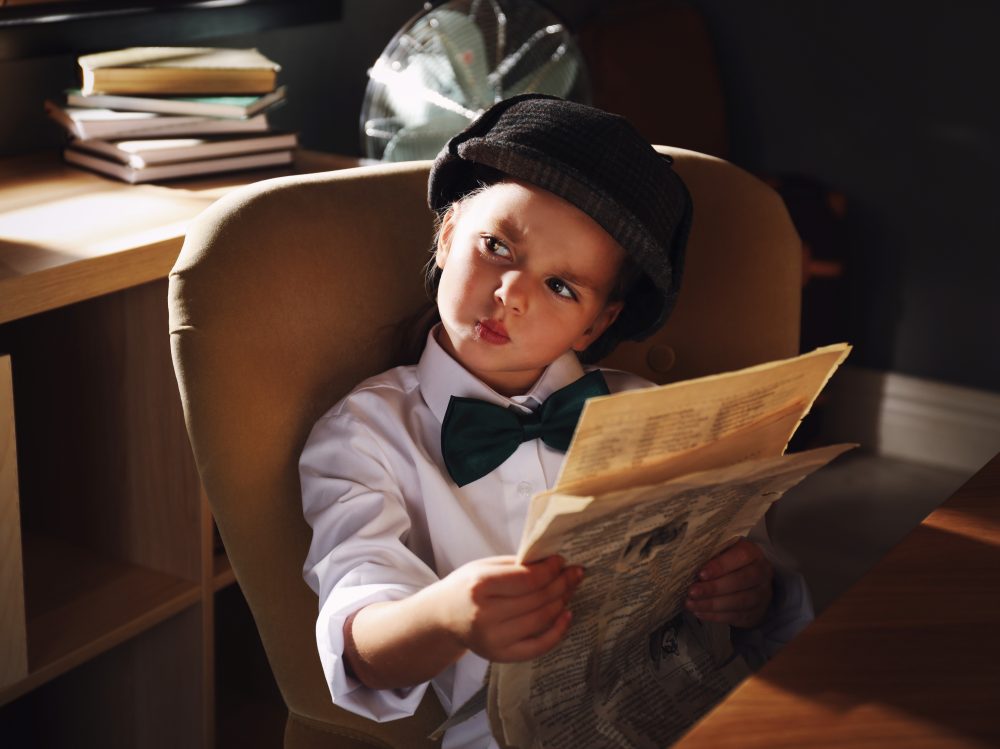 Cute little detective with newspaper in office